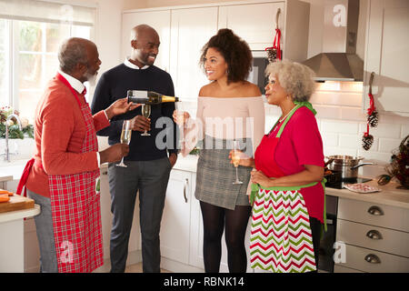 Hauts homme noir pouring champagne pour sa famille pour fêter Noël tout en préparant le dîner ensemble dans la cuisine Banque D'Images