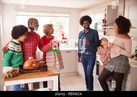 Course mixte, multi generation family de parler et de boire du champagne dans la cuisine pendant qu'ils préparent ensemble le dîner de Noël Banque D'Images