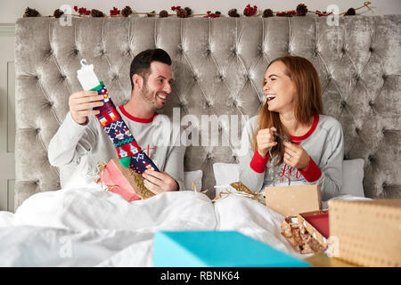 Vue avant du couple au lit à la maison de l'ouverture des cadeaux le jour de Noël Banque D'Images