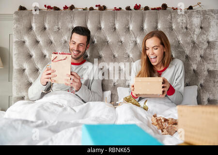 Vue avant du couple au lit à la maison de l'ouverture des cadeaux le jour de Noël Banque D'Images