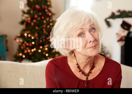 Portrait of Senior Woman Sitting on sofa dans le salon à la maison le jour de Noël Banque D'Images