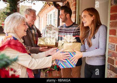 Les grands-parents d'être accueilli par sa famille alors qu'ils arrivent pour visiter le Jour de Noël avec des Cadeaux Banque D'Images