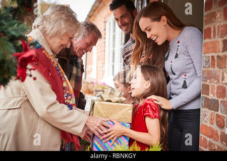 Les grands-parents d'être accueilli par sa famille alors qu'ils arrivent pour visiter le Jour de Noël avec des Cadeaux Banque D'Images