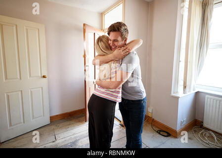 Jeune couple Hugging excité par la porte avant de New Home Banque D'Images