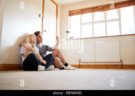 Couple Sitting on Floor In Empty Room de nouvelle conception de la planification d'accueil Banque D'Images
