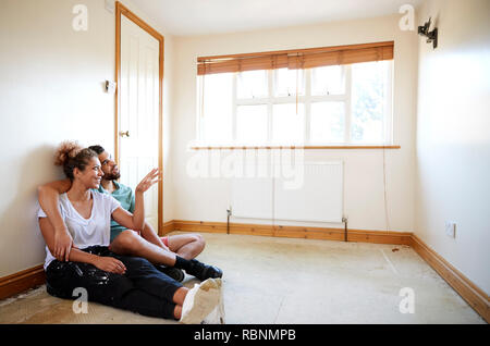 Couple Sitting on Floor In Empty Room de nouvelle conception de la planification d'accueil Banque D'Images