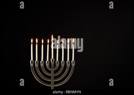 Les Chandelles sur Metal Hanukkah Menorah contre Black Background Banque D'Images