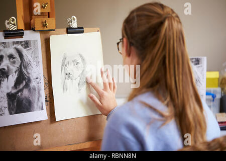 Vue arrière de l'artiste adolescent féminin assis à dessin Photo de chevalet a partir de photo de chien en strass Banque D'Images