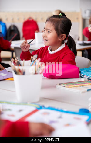 Close up de jeunes Chinois lycéenne portant l'uniforme scolaire assis à un bureau dans une petite école de classe, selective focus, vertical