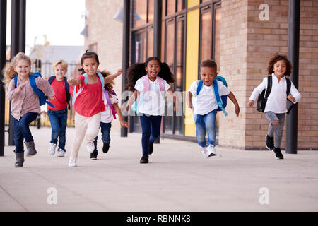 Un groupe multi-ethnique de l'école s'exécutant dans un passage à l'extérieur de leur bâtiment de l'école infantile après une leçon Banque D'Images