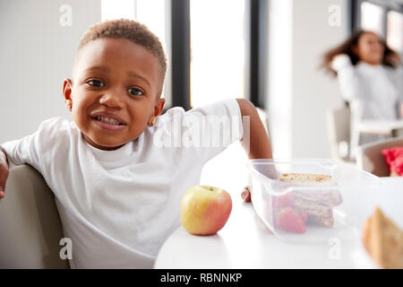 Jeune écolier noir assis à une table dans une classe de maternelle pendant sa pause déjeuner, Close up Banque D'Images