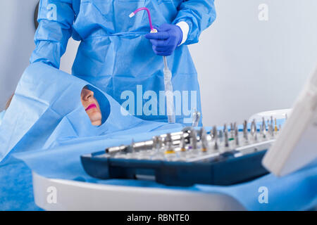 Dentiste en uniforme bleu d'effectuer la chirurgie d'implant dentaire Banque D'Images