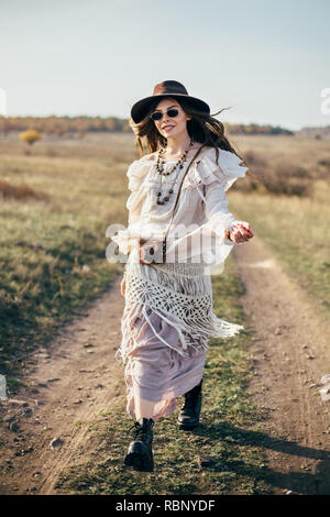 Belle fille hippie dans hat marche sur route dans la nature. Style de la liberté Banque D'Images