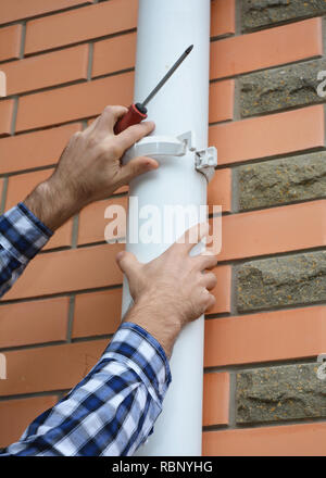 L'installation de l'entrepreneur et de réparation du système de gouttière en PVC pipe-line. Gouttières, Chêneaux, plastique et drainage par homme à mains. Banque D'Images