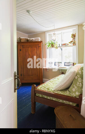 Chambre avec lit simple en bois et de la vieille armoire bois à l'intérieur d'une ancienne maison de style cottage 1862 Banque D'Images