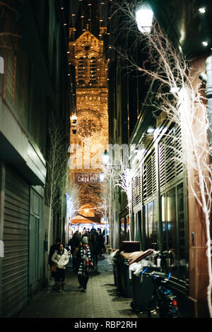 STRASBOURG, FRANCE - DEC 23, 2016 : des piétons circulent sur le marché de Noël à Strasbourg avec la petite rue Cathédrale illuminée en arrière-plan Banque D'Images