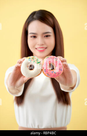 Belle jeune femme asiatique portaient des t-shirt blanc, sourire et bonne humeur, eating, isolé sur fond jaune Banque D'Images