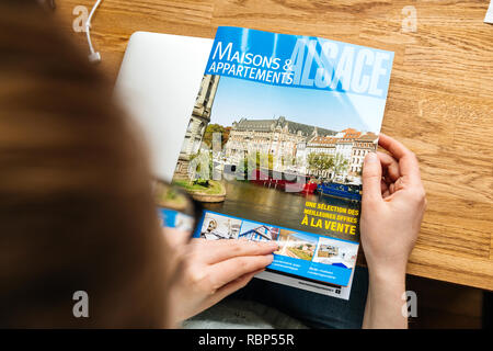 PARIS, FRANCE - Apr 26, 2017 : Vue de dessus de femme lisant Maisons et Appartements avec catalogue immobilier immobilier à louer et acheter en France, l'Alsace Maisons et Appartements Alsace Banque D'Images