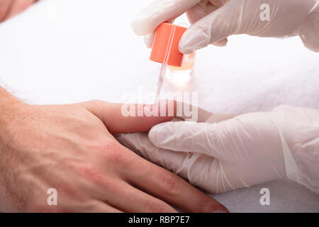 Close-up de l'application de l'huile de beauté des ongles sur la main de l'homme à Spa Banque D'Images
