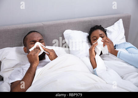 L'Afrique malade jeune couple Lying On Bed Blowing leur nez dans la chambre Banque D'Images