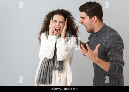 Photo de contrarié l'homme et la femme crier tout en luttant contre des sur fond gris Banque D'Images