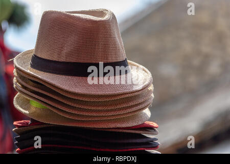 Une pile de paille chapeaux fedora en plusieurs couleurs avec des bandes de couleurs différentes avec un arrière-plan flou out Banque D'Images