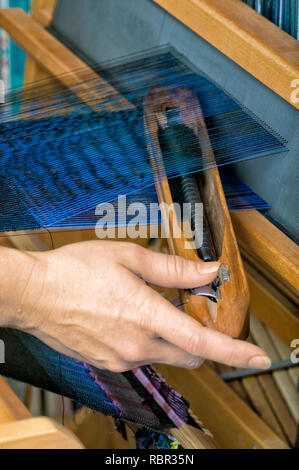 Close-up de lancer la navette sur un métier à tisser en bois avec un textile qui est un double-double couche de tissu, bleu et noir couches étant tissés. Banque D'Images