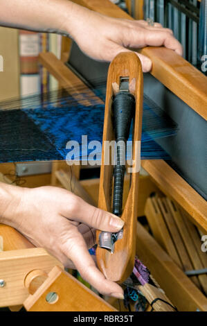 Close-up d'un AVL inverseur sur un métier à tisser en bois avec un textile qui est un double-double couche de tissu, bleu et noir couches étant tissés. Banque D'Images