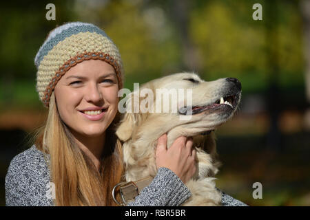 Portrait of smiling, jolie blonde et golden retriever pure race, chien, vue en gros contre green bokeh Banque D'Images