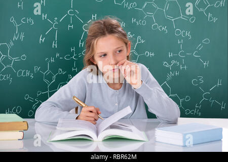 Portrait d'un élève en face de formules chimiques On Chalkboard Banque D'Images