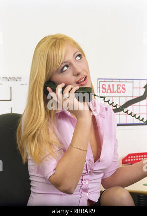 Blonde girl talking on telephone in office Banque D'Images