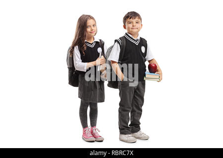 Portrait d'une écolière et écolier en uniforme holding books et posant isolé sur fond blanc Banque D'Images