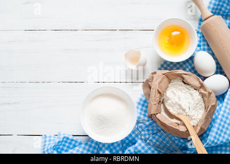 Ingrédients pour la cuisson la boulangerie - farine, oeuf, sucre, rouleau à pâtisserie sur la table en bois blanc. Banque D'Images