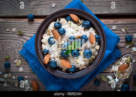 Avoine avec des bleuets, d'amandes, graines et coconat à table en bois rustique. Mise à plat. Banque D'Images