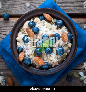 Avoine avec des bleuets, d'amandes, graines et coconat à table en bois rustique. Mise à plat. Banque D'Images