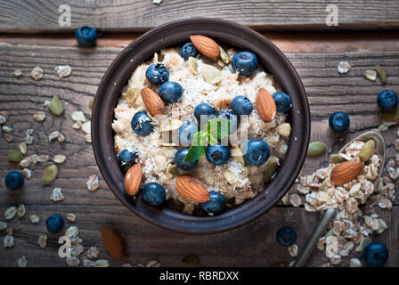 Avoine avec des bleuets, d'amandes, graines et coconat à table en bois rustique. Mise à plat. Banque D'Images