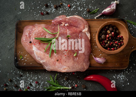 La viande de porc cru. La viande steak aux épices et herbes sur le tableau en ardoise. Mise à plat avec. Banque D'Images