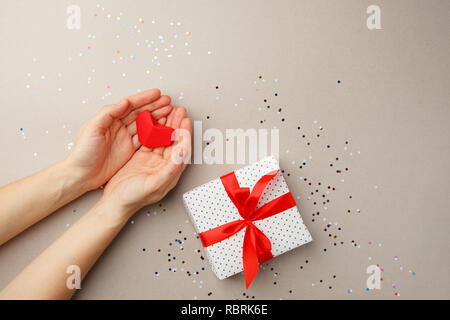 Female hands holding Guns N Roses au-dessus de table gris. Vue d'en haut. Mère Noël valentine day gift wrapping, copie, espace télévision lay Banque D'Images