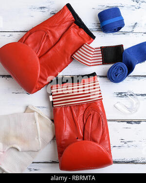 Paire de gants de boxe en cuir rouge, bleu, pansement textile Protection silicone pour les dents sur un fond en bois blanc, vue du dessus Banque D'Images