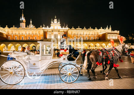 Cracovie, Pologne - 28 août 2018 : chevaux à l'ancienne Coach Transport Déménagement près de Cloth Hall Building à la place de la vieille ville, dans une nuit d'été. Banque D'Images