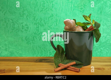 Mug vert avec des ingrédients à base de plantes naturelles sur fond vert Banque D'Images