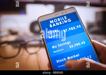 Main holdding Sexe masculin avec un smartphone à l'écran mobile banking avec arrière-plan bureau floue Banque D'Images