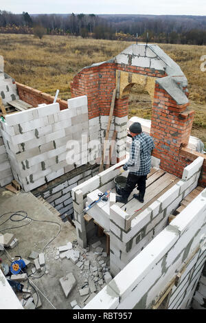 Le maître, à l'aide d'une truelle, colles gasblocks avec une solution de colle sur le site de construction 2018 Banque D'Images