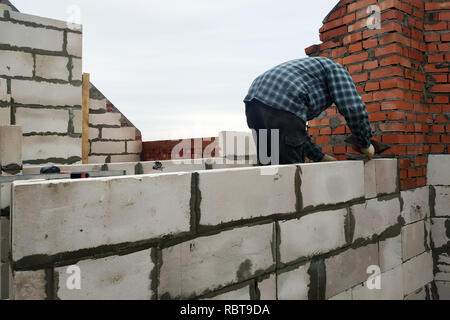 Avec l'aide de la solution de colle, le travailleur construit un mur de blocs de gaz 2018 Banque D'Images