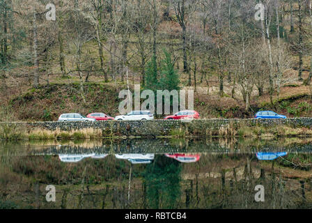 Yew Tree Tarn et voitures en stationnement reflète dans le Tarn, près de Coniston, Lake District, Cumbria Banque D'Images