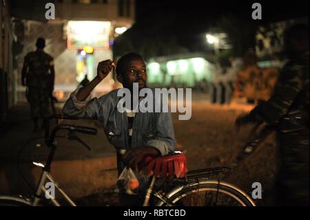 Un homme fume une cigarette pendant que les soldats éthiopiens, dans le cadre de la Mission de l'Union africaine en Somalie, la conduite d'une patrouille de nuit à travers la ville de Baidoa, la Somalie, le 22 juin. Photo de l'AMISOM - Tobin (14332224890). Banque D'Images