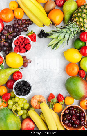 Cadre fait de fruits mûrs, Fraises Framboises Oranges Pommes Prunes Raisins kiwis mangues bleuets sur le kaki, vue de dessus de table blanc Banque D'Images