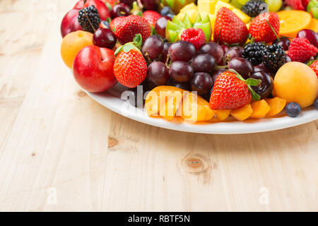 Plateau de fruits sains, Fraises Framboises Oranges Pommes Prunes Raisins kiwis mangues bleuets persimmon sur table en bois, copie du texte pour l'espace Banque D'Images