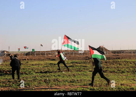 Manifestant palestinien vu tenant un drapeau au cours d'affrontements entre les citoyens palestiniens et les forces israéliennes d'occupation tout en protestant contre la reconnaissance de Jérusalem comme capitale d'Israël par le président américain, Trump, à l'est de la ville de Gaza. Banque D'Images