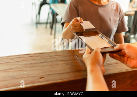 Waiter servir le café avec un ordinateur portable et des verres sur la table de travail dans le café. Banque D'Images